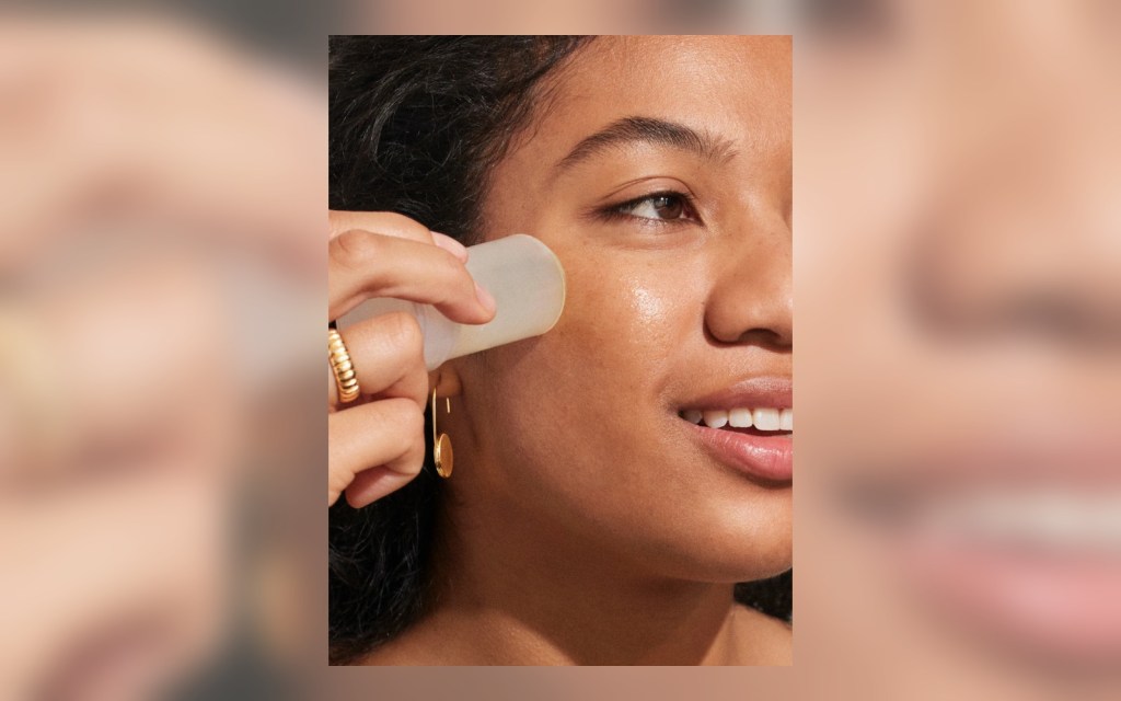 SPF stick being applied over cheek makeup