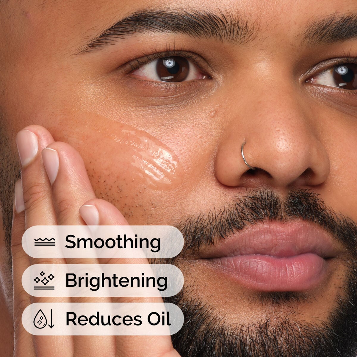 Person applying clear niacinamide serum across one cheek