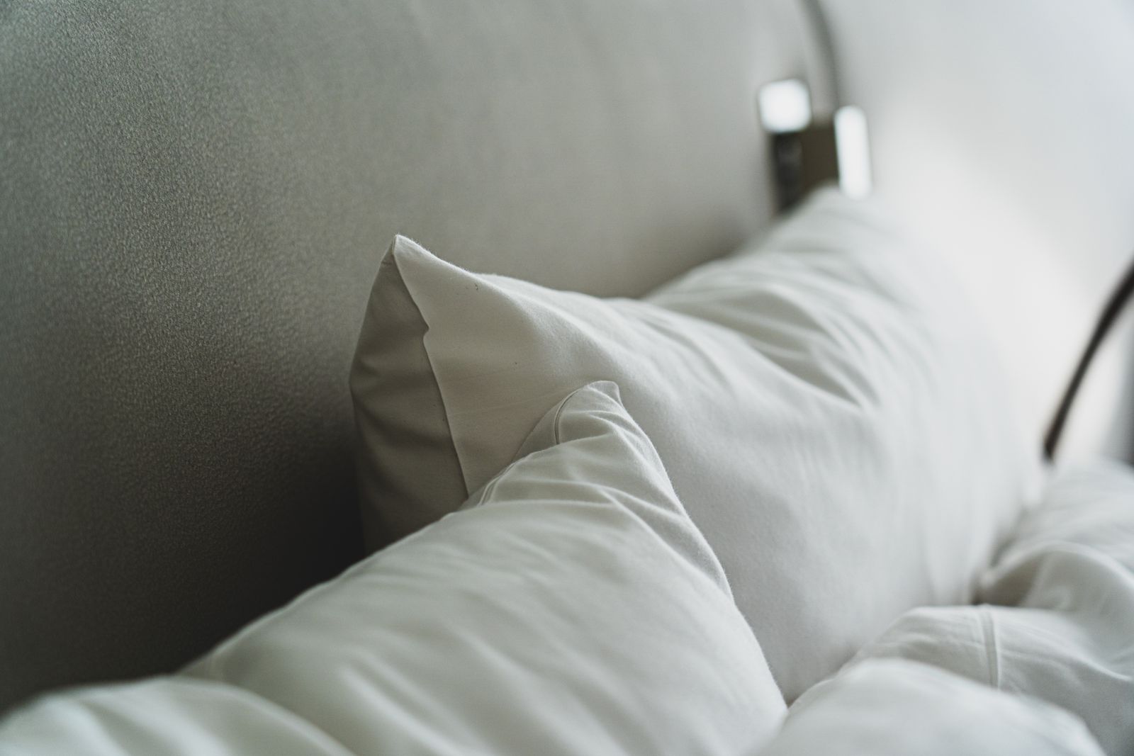 White pillows in plain pillowcases rest against an upholstered headboard